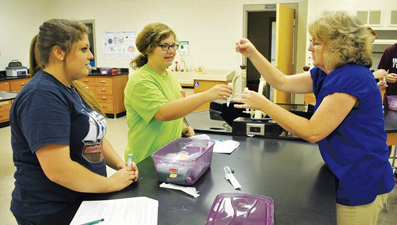 DAILY LEADER / RHONDA DUNAWAY / Krista Davis (from left) and Abby Burke get hands-on training with lab equipment from Enterprise Attendance Center science teacher Kathy McKone during lab work for their Biomedical Technology course Monday. The students were working on a project where they will extract their own DNA to study.