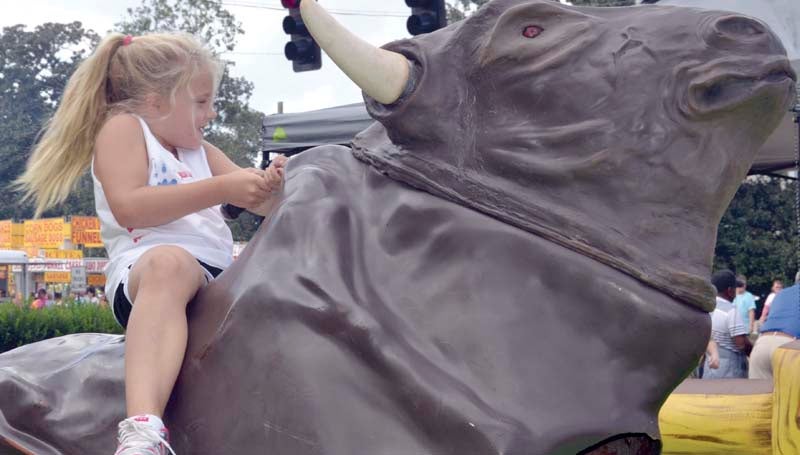 DAILY LEADER / RACHEL EIDE / Alli Ferguson, 8, of Brookhaven hangs on for a ride on the mechanical bull in the Ole Brook Festival kids' area. 