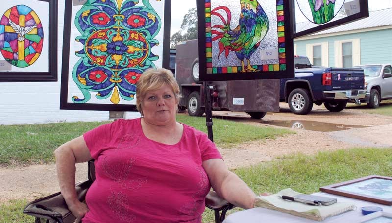 Martha Williamson surrounds herself with handmade stained-glass creations at the Wesson Flea Market Saturday.