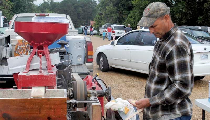 Dewitt Parrett examines freshly ground cornmeal produced onsite by his portable mill at the Wesson Flea Market Saturday. The flea market is staged each year by the Wesson Volunteer Fire Department, drawing crowds of shoppers to the town's downtown area.
