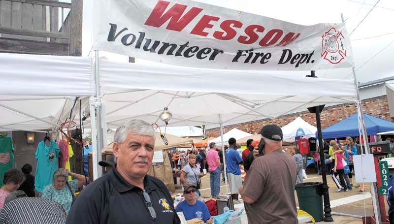 David Clanton, with the state fire marshal's office, teaches kids about fire safety as he stands in front of the Wesson Volunteer Fire Department booth at the flea market Saturday.