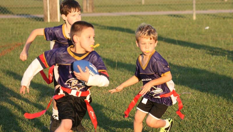 Ravens running back Gavin Hawley (center) looks for some running room as David Williams and Madison Williams prepare to lead the way Tuesday in BRD 5-to-6-year-old flag football action at the Hansel King Sportsplex.