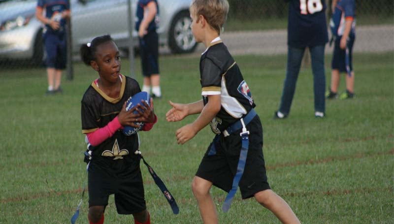 DAILY LEADER / MARTY ALBRIGHT / BRD Saints running back Angel Wilkinson (left) receives a handoff from Manny Miller. The Saints blanked the Bears 36-0 Tuesday to advance to the championship game and play the 49ers Saturday in 7-to-9-year-old flag football action at the Hansel King Sportsplex.