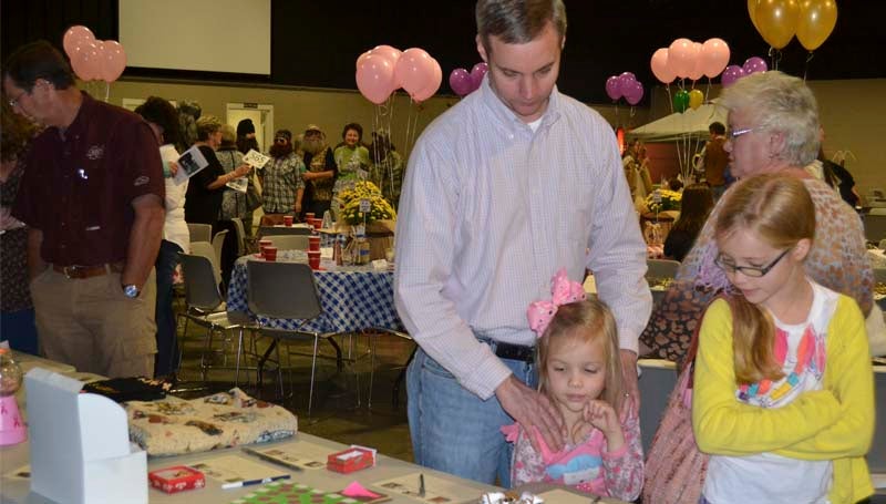 Tim Slay and daughters Abby and Ellie Slay look over the silent auction items Monday night.