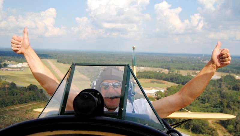 DAILY LEADER / TAMMIE BREWER / Barnstormer Ted Davis gives the two-thumbs up sign (above) during a flight over the Brookhaven area Monday afternoon shortly after takeoff from the Brookhaven Airport. Davis of Brodhead, Wis., brought his 1929 New Standard Biplane (right) to Brookhaven as part of the Biplane Rides of America Dixieland Tour and is offering rides for area would-be barnstormers.