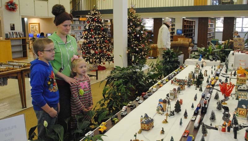 THE DAILY LEADER / RHONDA DUNAWAY / Ten-year-old John Paul Farr (left), of Brookhaven, and his little sister, Carly Farr, 6, examine details of Maxine Allen's Christmas Village with library intern Alexis Smith, 22, of Brookhaven, in the lobby of the Lincoln County Public Library Wednesday afternoon. Allen has been setting up her snow village in the library lobby each Christmas season for the last several years. "I started collecting 18 years ago when co-worker, Carolyn Douglas, gifted me with a church and a library," Allen said. "Family, friends and co-workers have been finding pieces to go in my set since then. Currently, I am looking for a pharmacy and a hospital to complete the village."