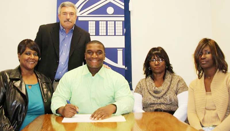 CO-LIN MEDIA / NATALIE DAVIS / DAMPEER SIGNS WITH AUBURN - Copiah-Lincoln Community College center Xavier Dampeer of Mendenhall (seated second from left) has signed with the Southeastern Conference Champion Auburn Tigers. Dampeer (6-2, 300) was a leader on for the Wolfpack offense this season. He moved from the defensive side of the ball to center and started in all nine games for the Wolfpack. Dampeer was named National Junior College Athletic Association (NJCAA) All-Region 23, Mississippi Association of Community/Junior College (MACJC) First Team All-State, and the MACJC Most Valuable Offensive Lineman. In his two years at Co-Lin, the Wolfpack posted a 16-5 record, winning the MACJC State Championship in 2012. Pictured with Dampeer are seated from left, his sister, Shiree Dampeer; his mother, Shirlee Dampeer, and his sister, Cristal Dampeer, all of Mendenhall; standing is Co-Lin head coach Glenn Davis.