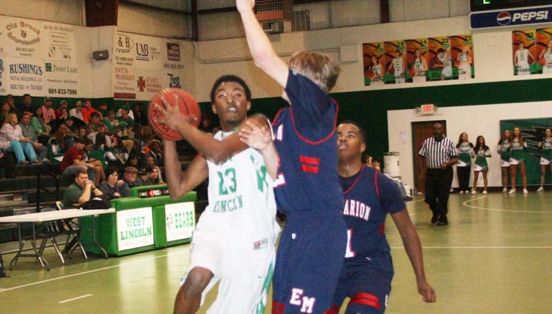 DAILY LEADER / MARTY ALBRIGHT / West Lincoln's Duane Marshall (23) drives in for a layup as East Marion defender Tre Tolar (32) stretches to blocked the shot Tuesday night in Jack Case Gymnasium.