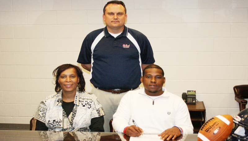 DAILY LEADER / MARTY ALBRIGHT /  Hill SIGNS WITH JONES COUNTY - Brookhaven defensive linebacker Tyris Hill has signed with the Jones County Community College Bobcats. Pictured with Hill are his mother Phyllis Hill (left) and (standing) Brookhaven head coach Tommy Clopton.