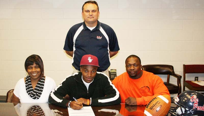 DAILY LEADER / MARTY ALBRIGHT /  SMITH SIGNS WITH SOUTHWEST - Brookhaven receiver and special team specialist Shuntez Smith has signed with the Southwest Community College Bears. Pictured with Smith are his mother Teresa Smith, (left) his dad, Gregory James, and (standing) Brookhaven head coach Tommy Clopton.