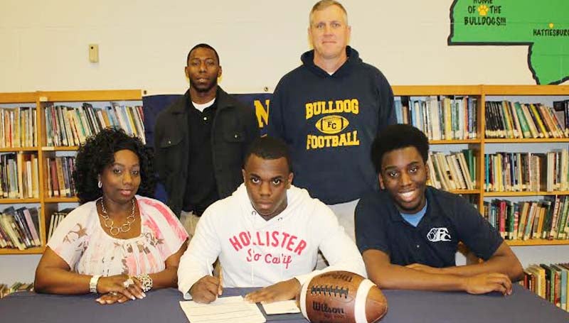 DAILY LEADER / STEPHANIE MCCORMICK / ROBINSON SIGNS WITH GULF COAST - Franklin County running back Chris Robinson has signed with the Mississippi Gulf Coast Community College Bulldogs. Pictured with Robinson are his mother, Rachel Harris; brother, Ken Robinson; and (standing) Franklin County coaches Jonathan Brooks and Adam Barron.