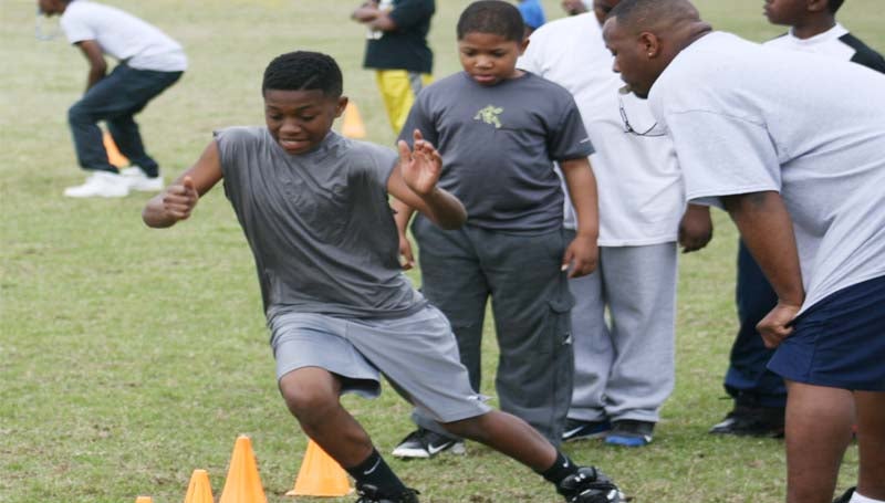Jontavious Wilkinson practice hits his foot skills in a drill run as coach Jason Dixon (right) looks on during Saturday's Brookhaven Southern Wildcats pee-wee registration day at Lipsey Middle School.
